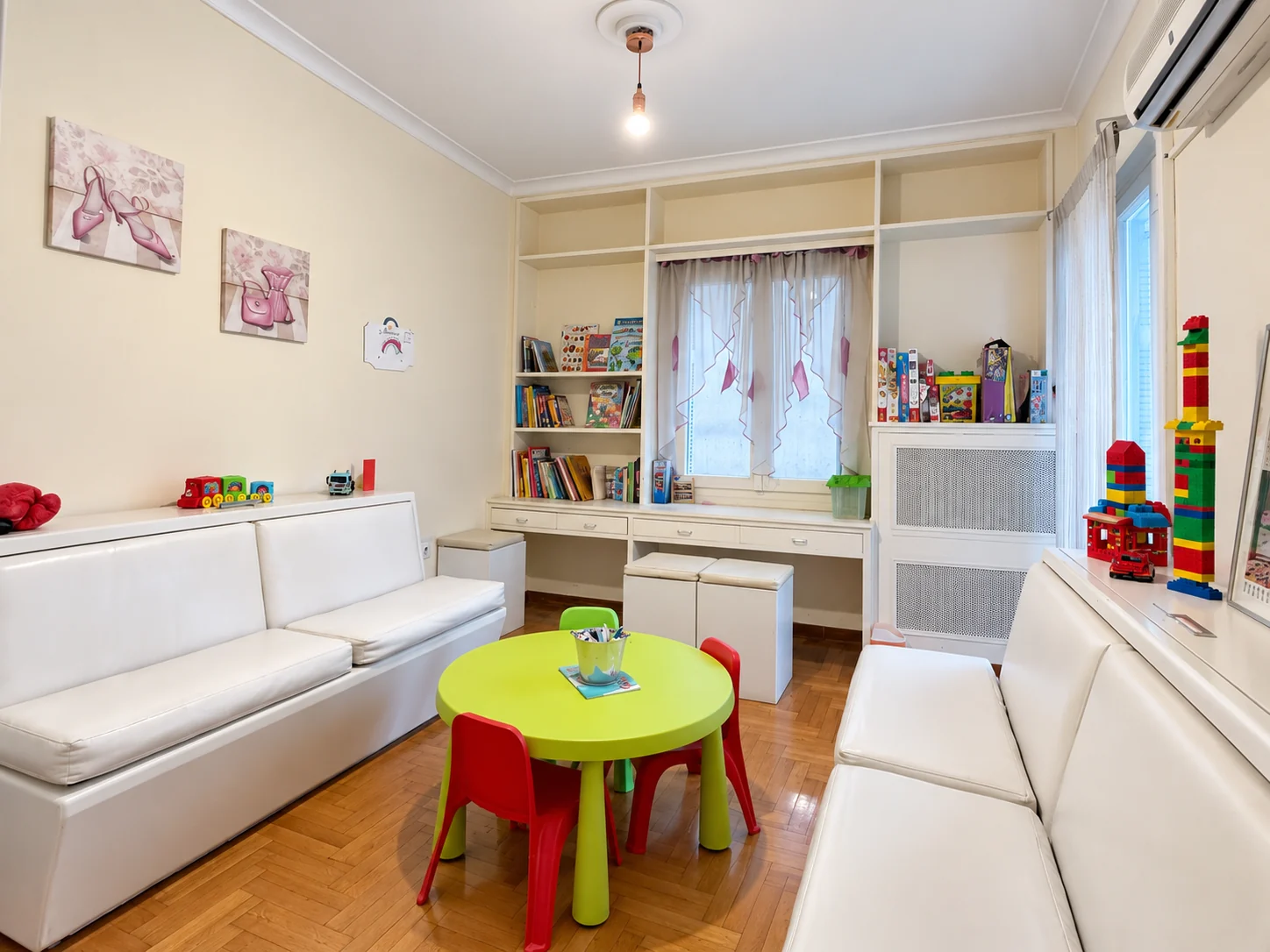 Children’s play area with a green table, colourful chairs, books and toys