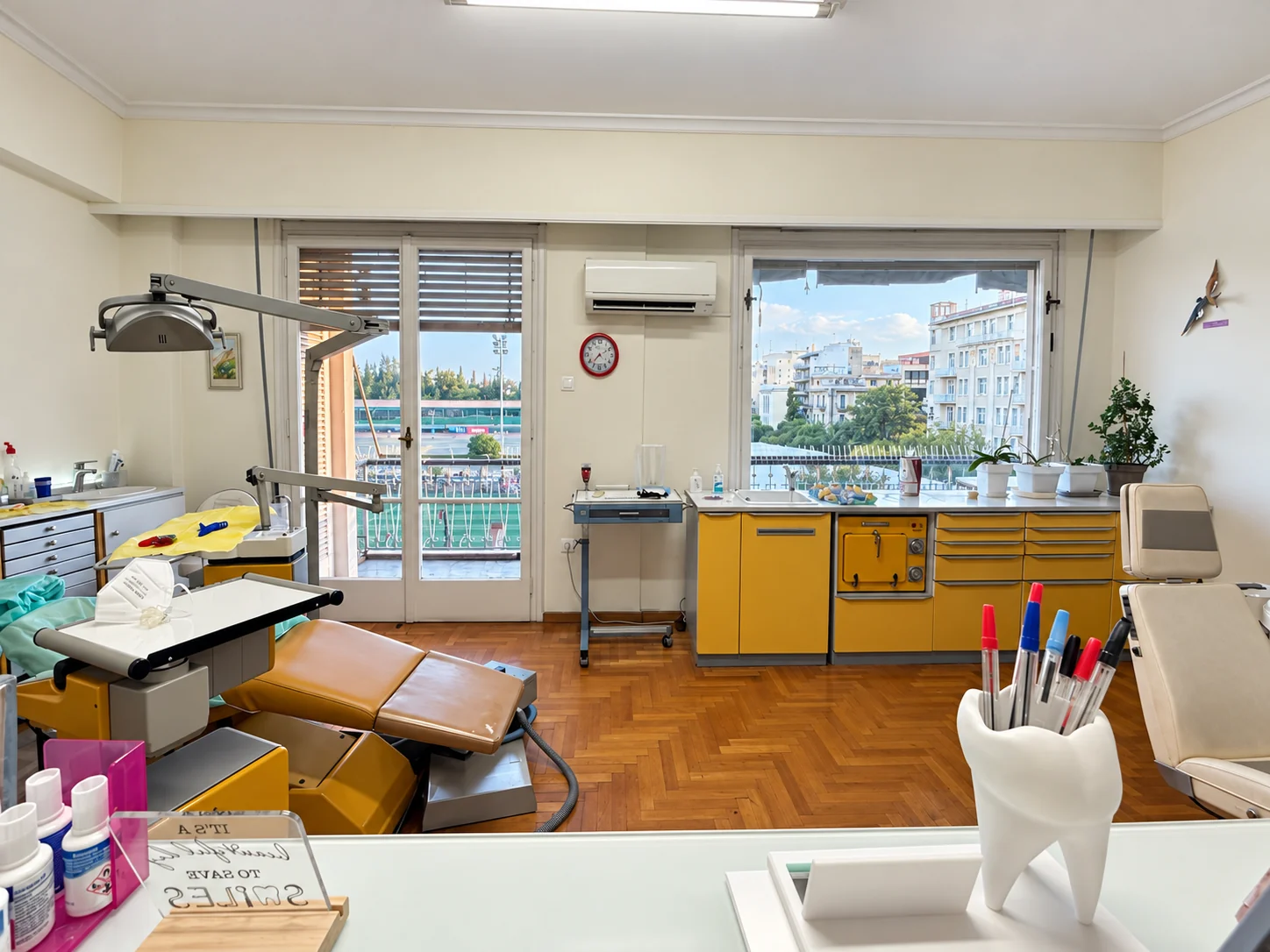 A bright treatment room with two dental chairs and yellow cabinets